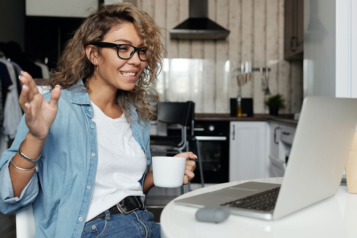 A woman smiling and attending an online meeting.